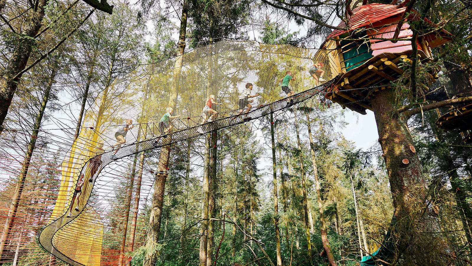Besuche den wildesten Spielpark im Wald. Macht es wie diese Kinder und rennt über die langen Hängebrücken von Baumhaus zu Baumhaus in den Baumkronen. Das ist ein Aktivurlaub für Familien mit Kindern.