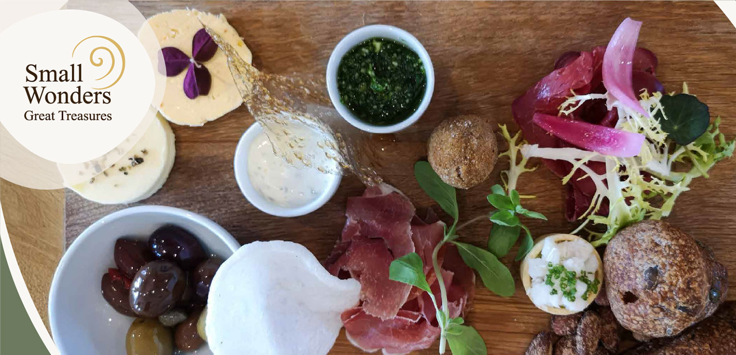 Anretning med lokale specialiteter som oste, oliven, skinke og dips set ovenfra. Introduktionsbillede til Gastroruten i Small Wonders.