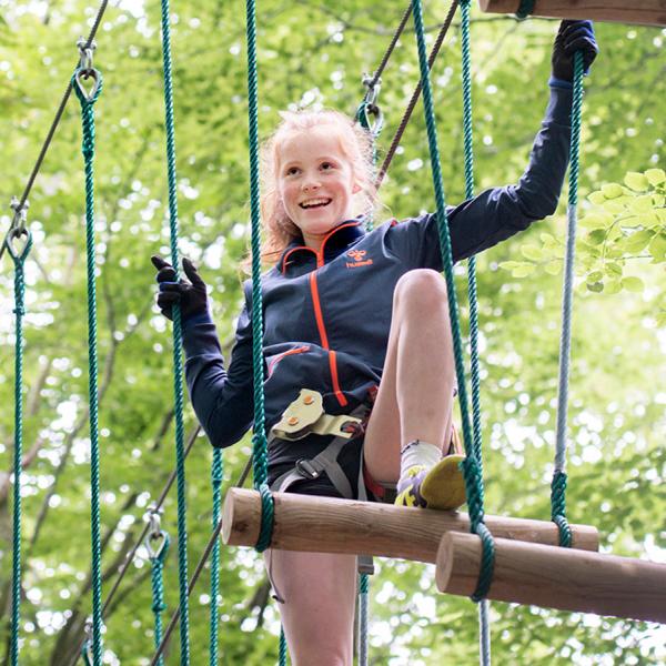 Go climbing, like this girl, in one of Vejle's beautiful forests. Fun family-friendly climbing tracks await. Enjoy an active family holiday at LEGOLAND® Billund and come home with lots of new nature experiences.
