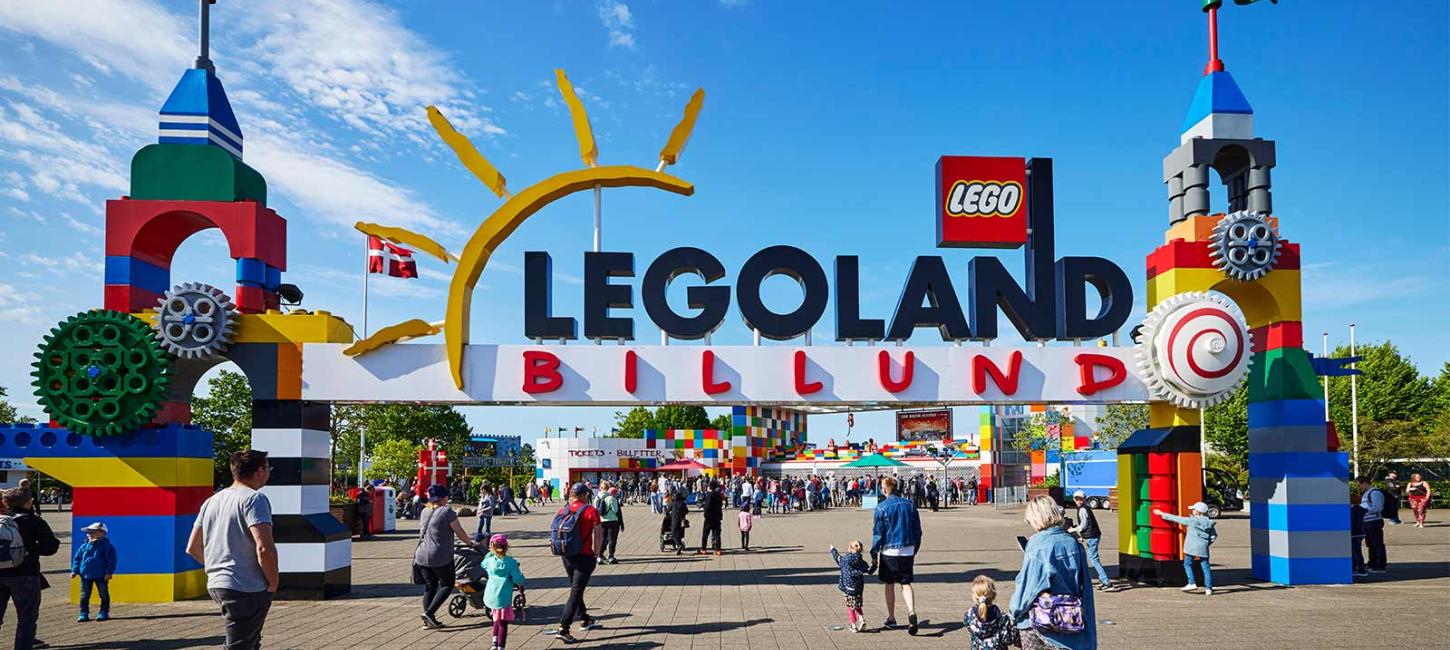 The gateway to LEGOLAND with the two LEGO® brick towers. A crowd of visitors coming to enjoy the park on a summer's day under a blue sky.