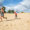 En pige og hendes lillebror har det sjovt med at løbe ned af sandklitten. Grene Sande. En naturoplevelse for hele familien i LEGOLAND Billund Resort.