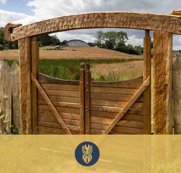 A carved wooden gate into the Lejre Land of Legends. The gate is built in strong beams with a snake head at each end of the overlying beam.